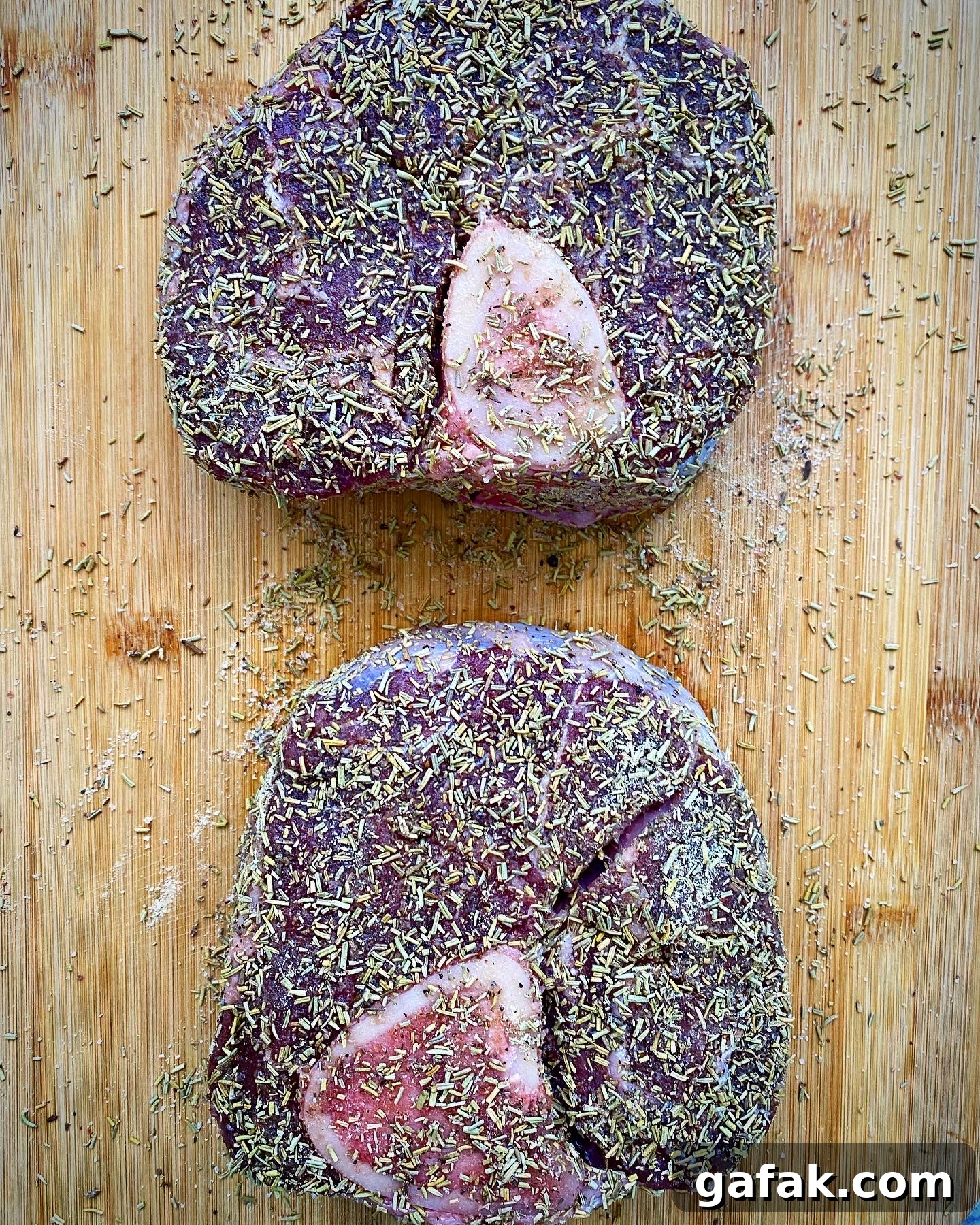 2 raw, seaoned beef shanks on a wooden cutting board