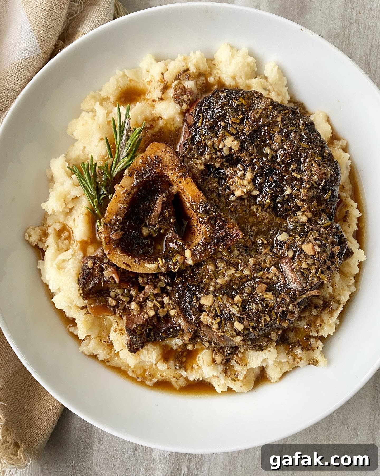 overhead shot of garlic herb beef shanks served over mashed cauliflower in a white bowl