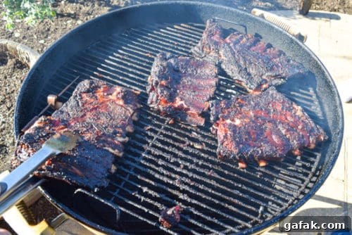 ribs being flipped on weber grill with spatula