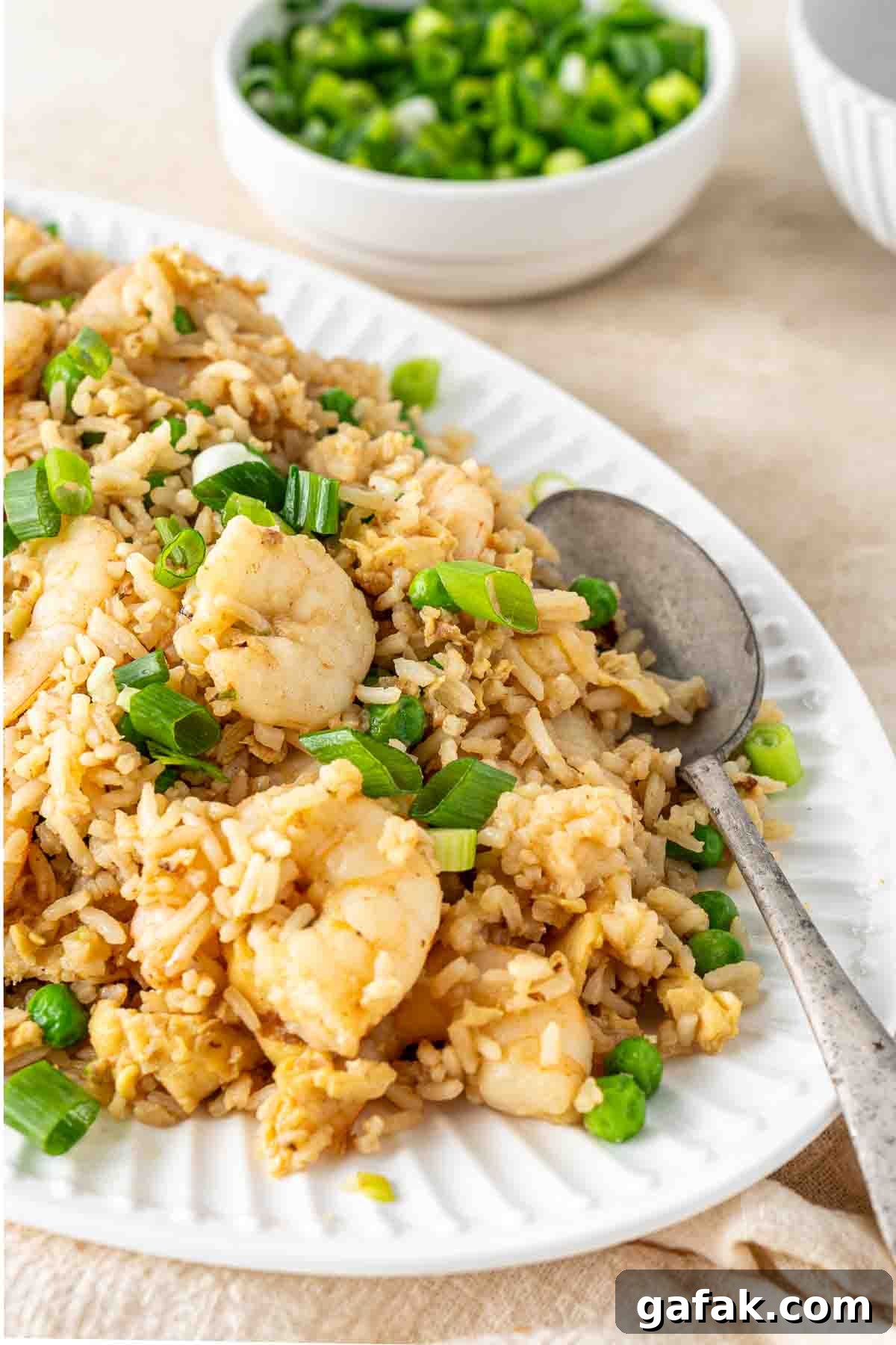 Garlic Prawn Egg Fried Rice Recipe for Quick Weeknight Meals 3 Prawn fried rice served onto a large plate with a spoon with green onions.
