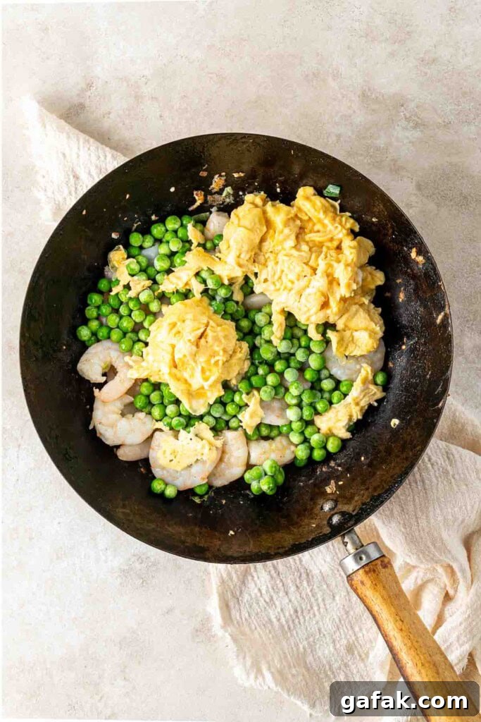 Garlic Prawn Egg Fried Rice Recipe for Quick Weeknight Meals 8 Prawns, peas and eggs in a wok.