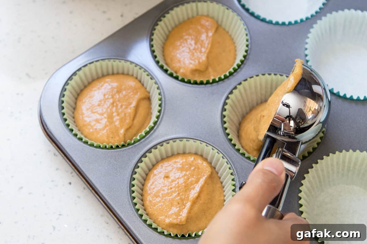Dividing the batter for the pumpkin cupcakes recipe with an ice cream scoop.