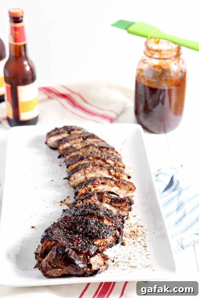 Dry rubbed Memphis Barbecue Ribs are served on a platter, shown with beer and barbecue sauce