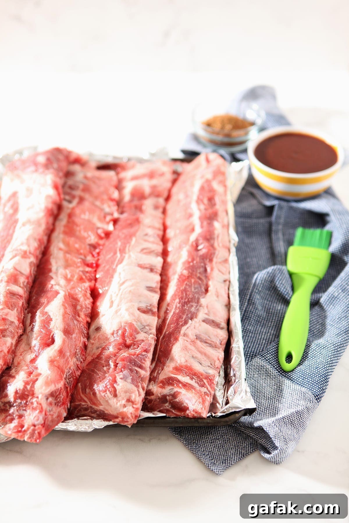 A baking sheet holds pork baby back ribs, before the ribs are baked