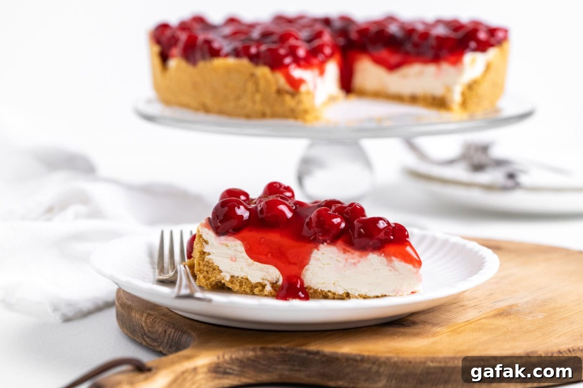 slice of no bake cherry cheesecake on plate with rest of cheesecake in background