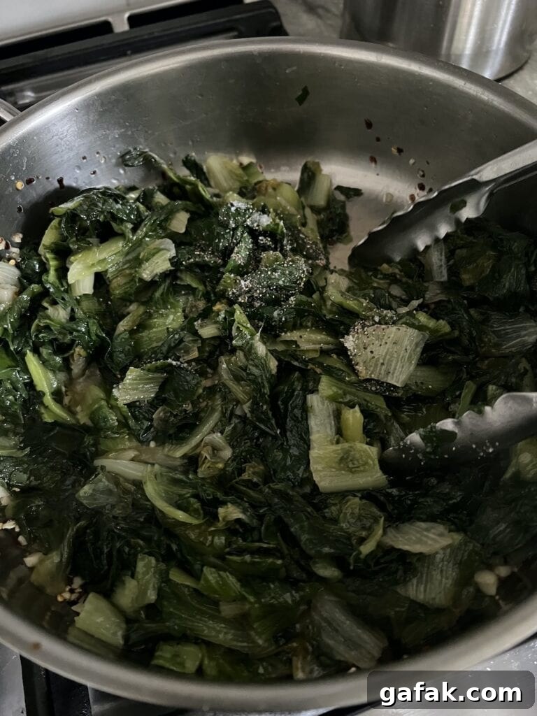 Stirring escarolein pan with tongs.