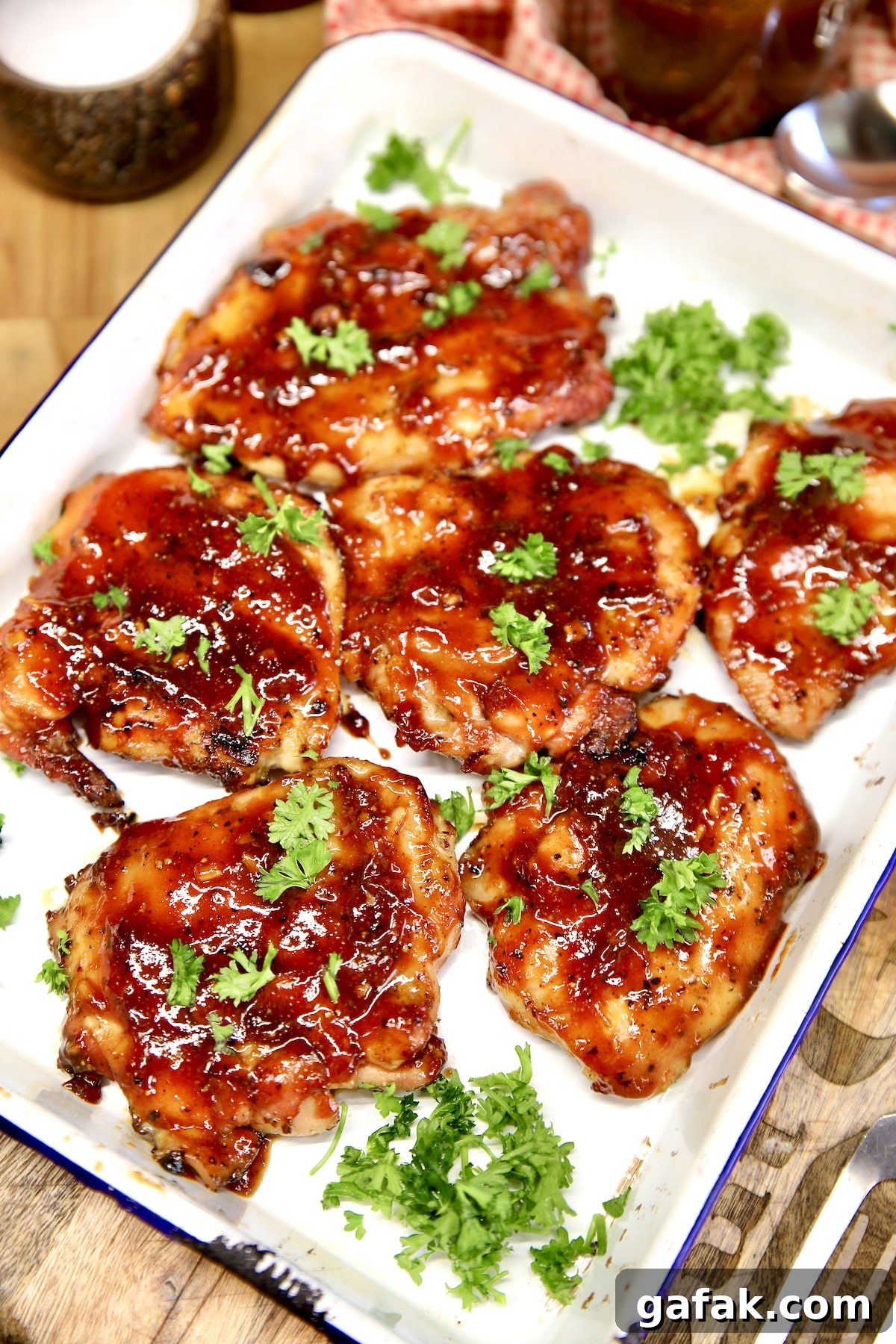Platter of bbq chicken thighs on a platter with parsley garnish.