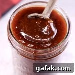 Sweet and Tangy BBQ Sauce in a jar with a wooden spoon