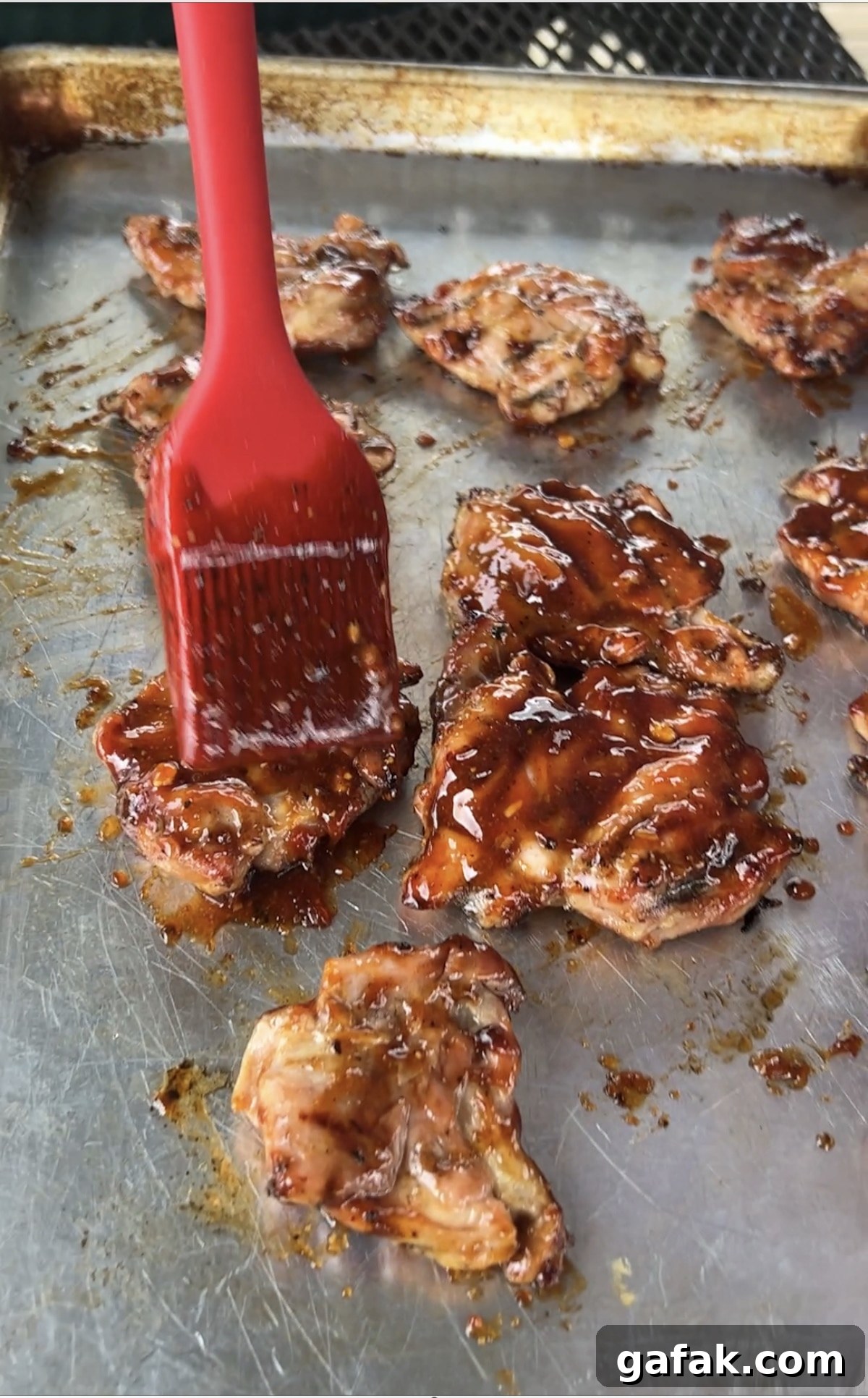 Brushing bbq sauce on grilled chicken.
