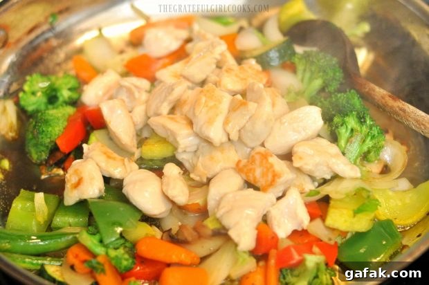 The cooked chicken is added to the vegetables in large skillet.
