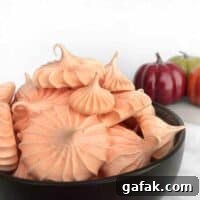 bowl full of orange pumpkin spice meringues with pumpkins in the background