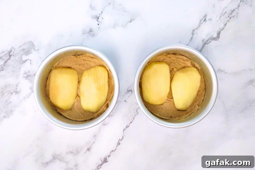 divide batter evenly into cake pans and press apples on top