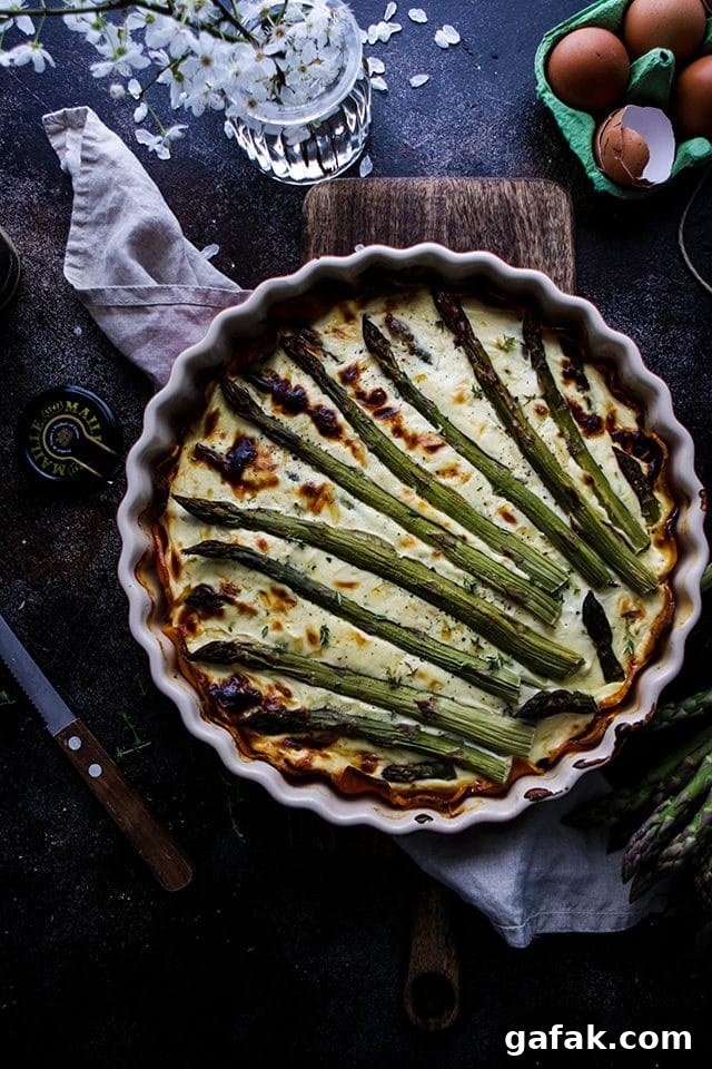 Asparagus Quiche in a Pie Pan After Baking Next to Eggs and a Knife