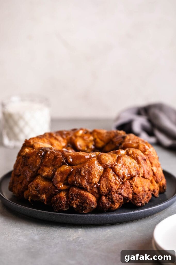 cinnamon roll monkey bread with pecan caramel sauce and a glass of milk in the back
