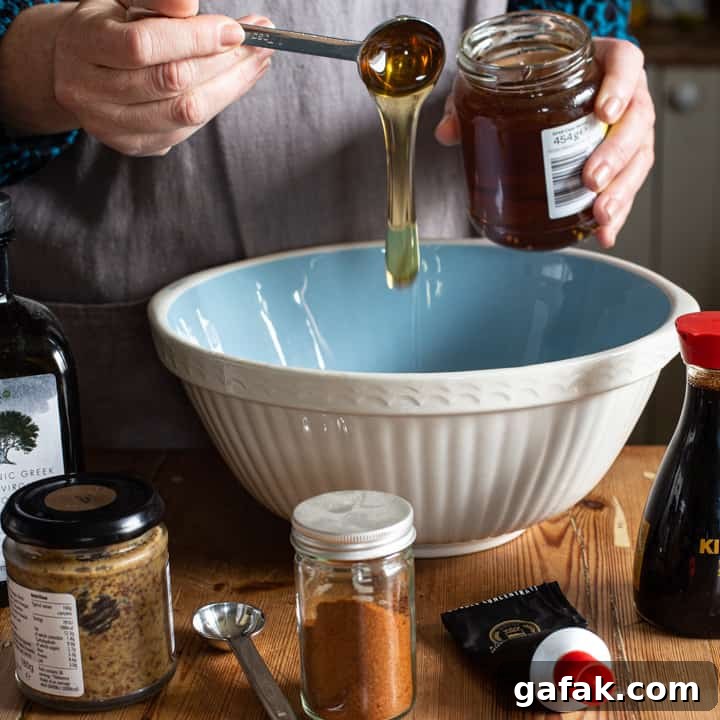 Sticky Honey Chicken Wings Recipe: Crispy Baked or Fried Wings 3 womans hands drizzling a silver spoon of honey into a large blue and white mixing bowl