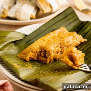 Unwrapped pasteles on a plate with a fork taking a piece out of the pasteles.
