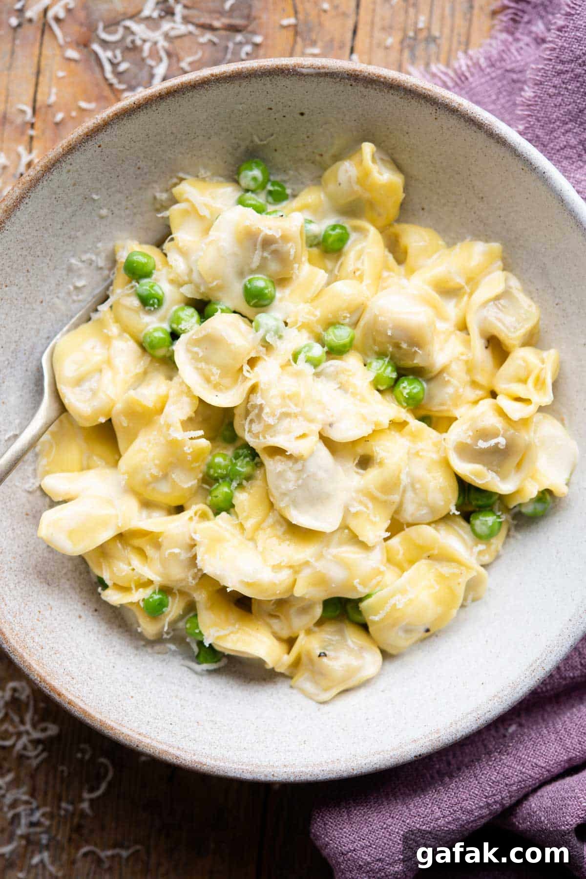 Creamy Tortellini in Parmesan Sauce 2 An overhead shot of Tortellini in a bowl with a cream sauce and peas