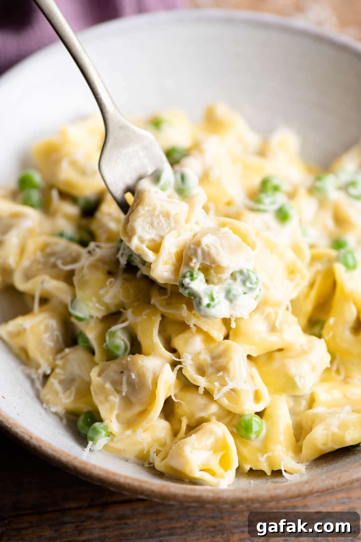 Creamy Tortellini in Parmesan Sauce 6 A close up of two Tortellini on a fork with cream and peas