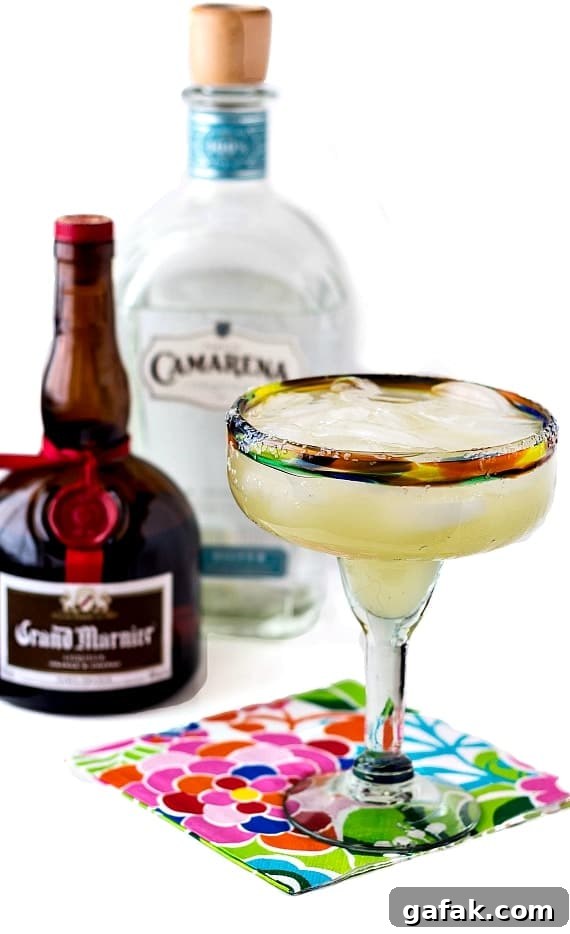 A frozen margarita next to liquor bottles.