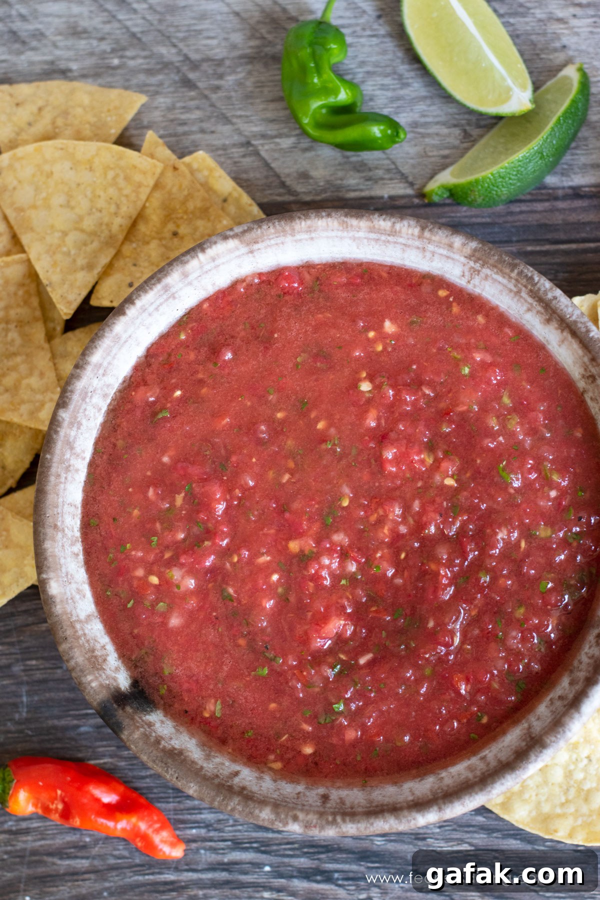 The top view of a bowl of padron pepper salsa. There are tortilla chips around the bowl.