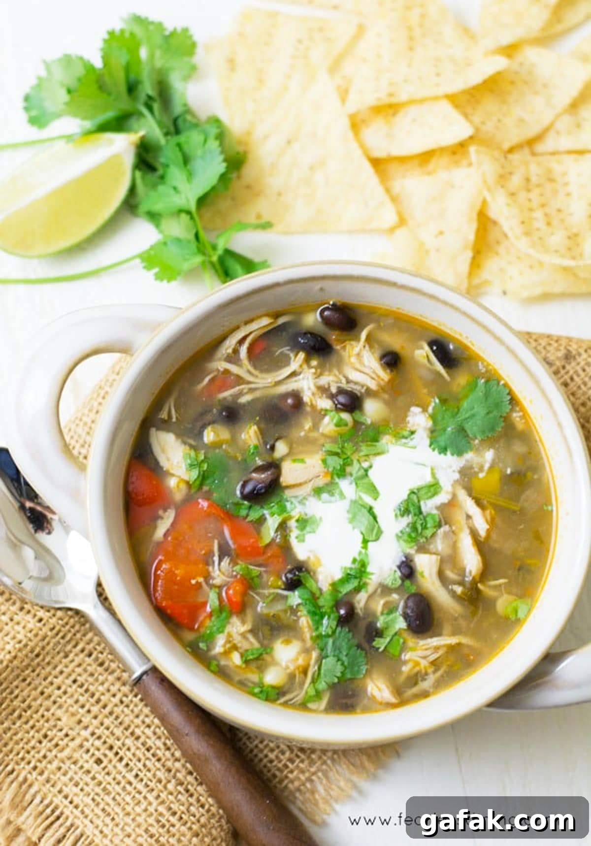 A top view of a bowl of taco soup with corn tortilla chips.