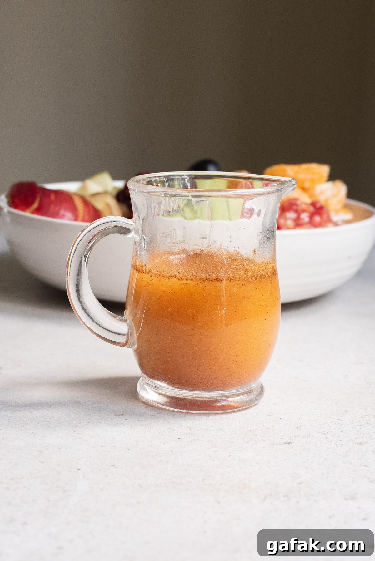Fruit salad dressing in a clear glass jug.
