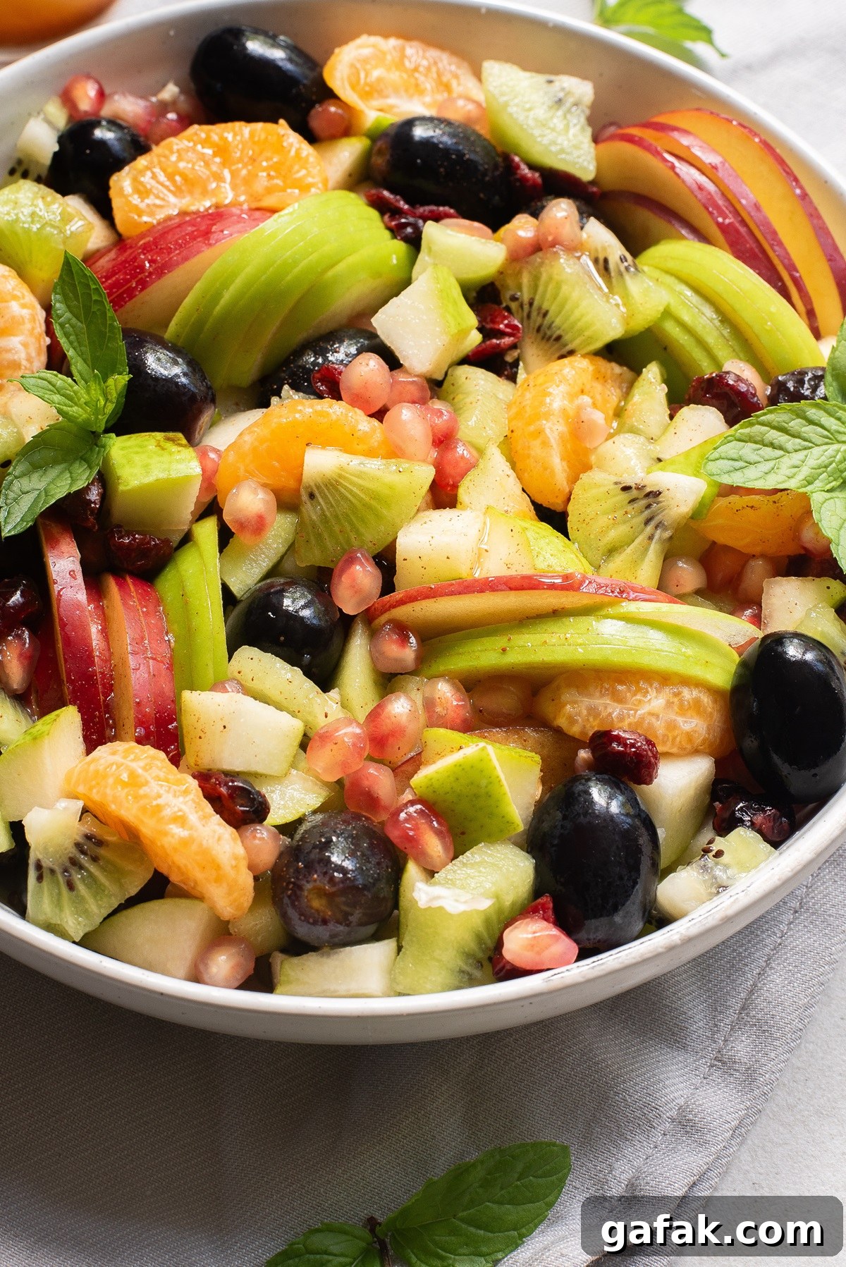 Close up view of various fruits in a white bowl.