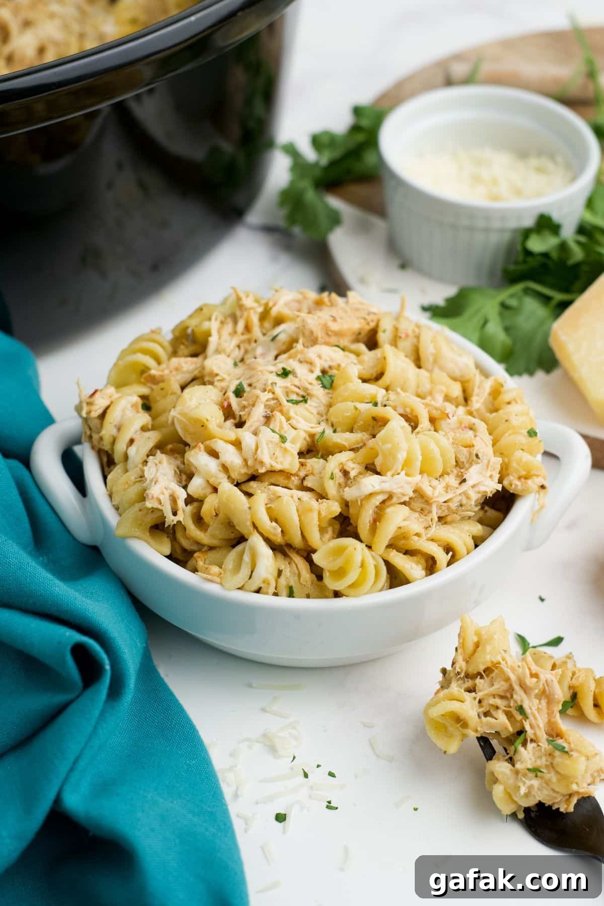 Garlic Parmesan Chicken Pasta in the Crockpot — Creamy Slow-Cooker Recipe 11 Crockpot garlic parmesan chicken in a bowl with a spoonful resting to the side.