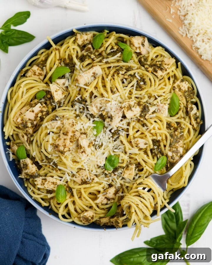 Overhead image of tuna pesto pasta in a bowl with fresh basil leaves and pasta twirled on a fork.