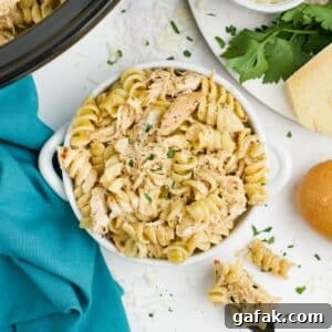Garlic Parmesan Chicken Pasta in the Crockpot — Creamy Slow-Cooker Recipe 16 Crockpot garlic parmesan chicken pasta in a bowl on the table with more in the slow cooker.