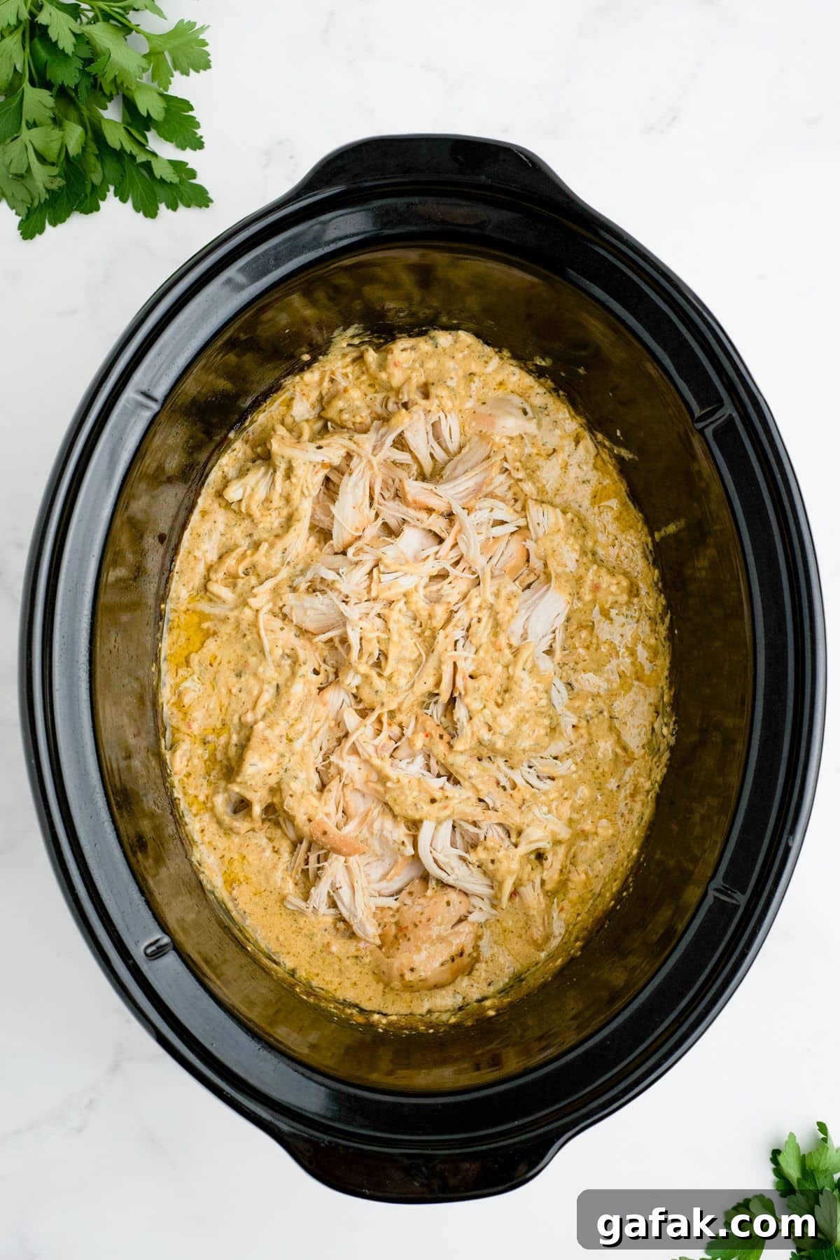 Garlic Parmesan Chicken Pasta in the Crockpot — Creamy Slow-Cooker Recipe 8 Chicken added to the sauce in a slow cooker.