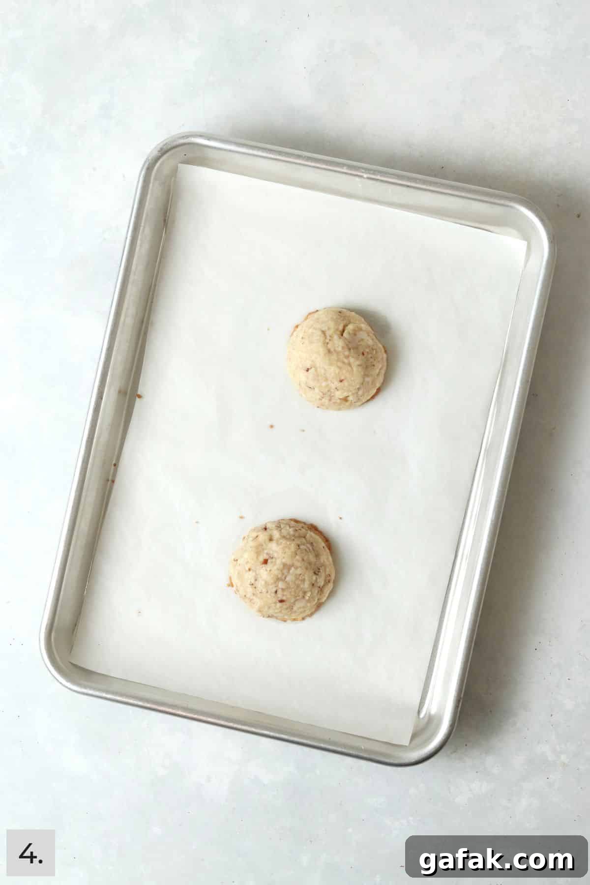 Snowball cookies baked on a baking sheet before powdered sugar.