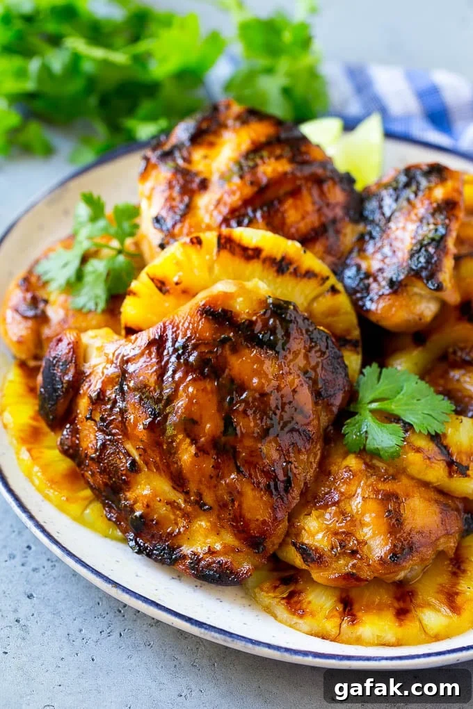 Grilled Hawaiian chicken thighs with pineapple and cilantro on a plate. Grilled Hawaiian chicken thighs with pineapple and cilantro on a plate.