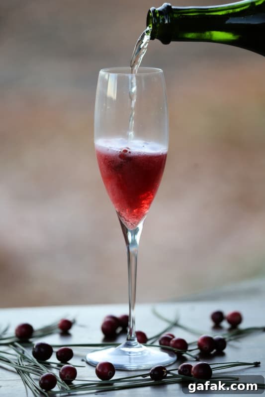 Champagne pouring into a champagne glass with cranberries in it