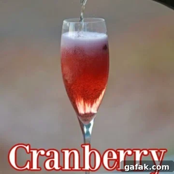 Cranberry Mimosa in a champagne glass with champagne pouring into the glass