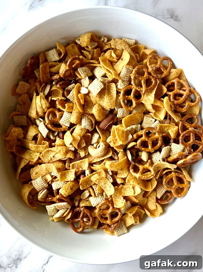Fritos mix combined in a large bowl with rice Chex, pretzels, and mixed nuts. 