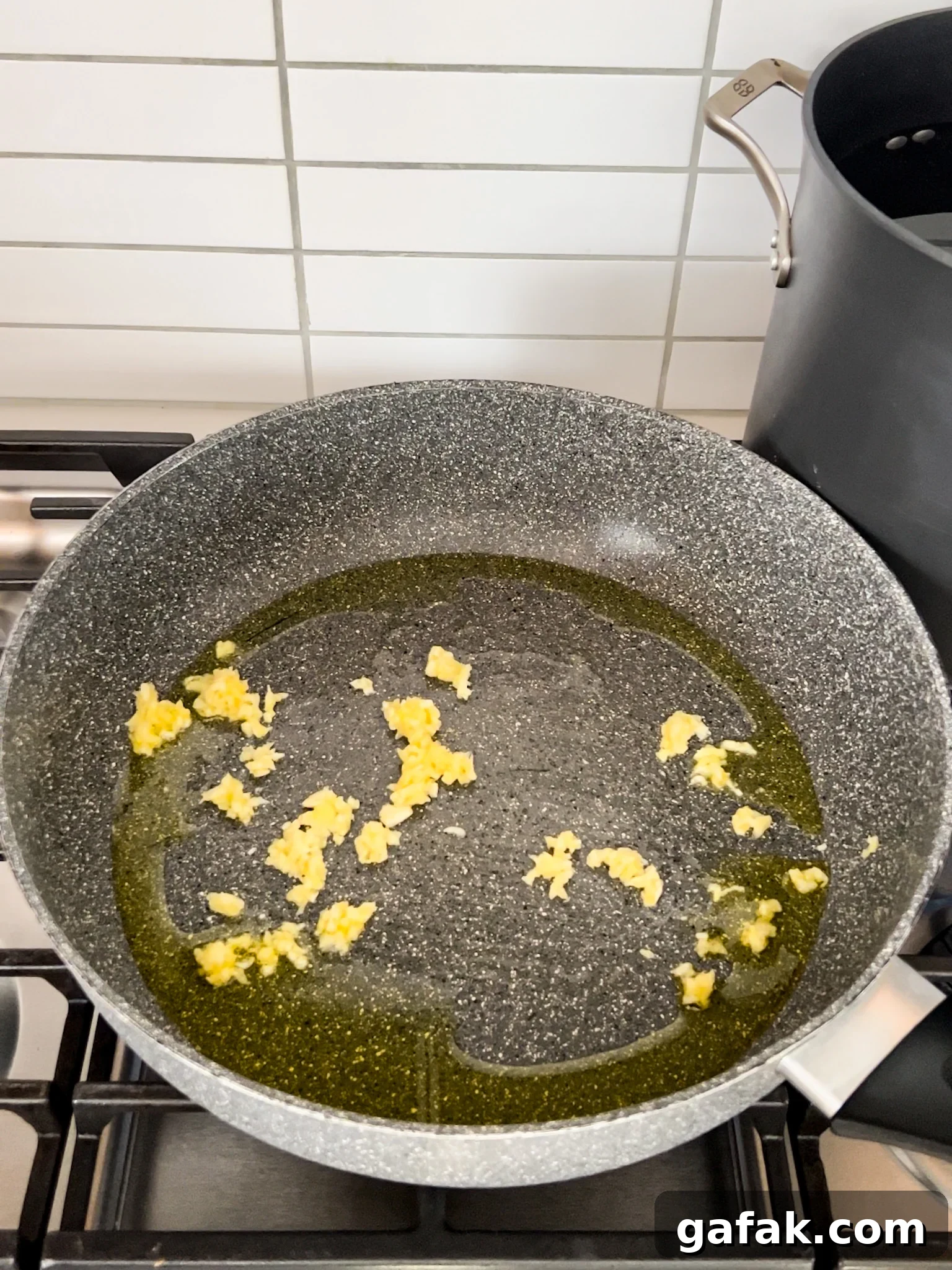 A pan on a stove with sautéed garlic and oil.