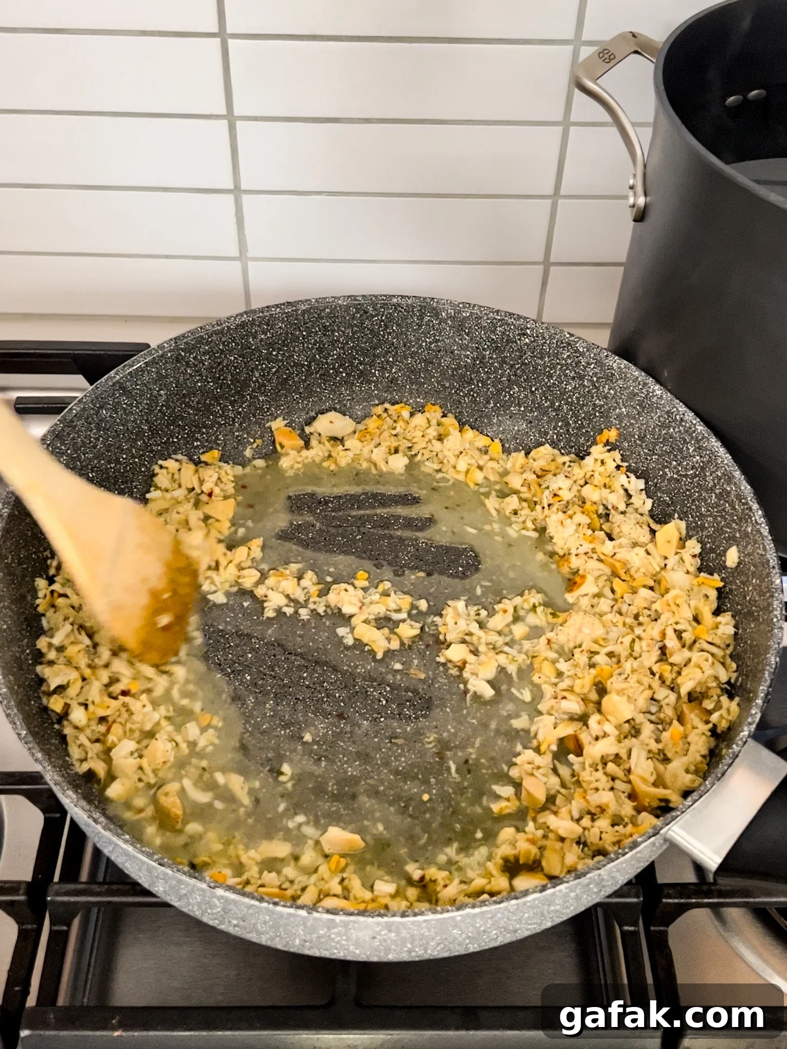 A pan with wine deglazing the contents of a pan on a stove.