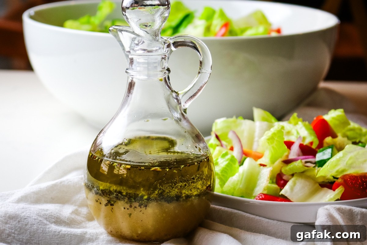 lemon olive oil dressing in a small salad dressing bottle with fresh green salad on the right side.