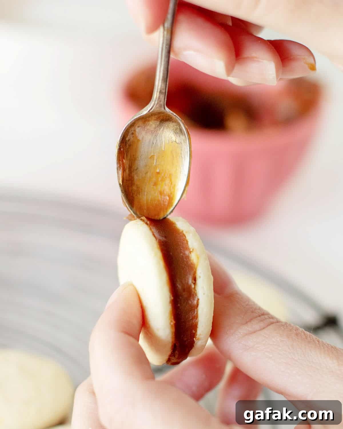 Smoothing out with a teaspoon the edges of an alfajor filled with dulce de leche.