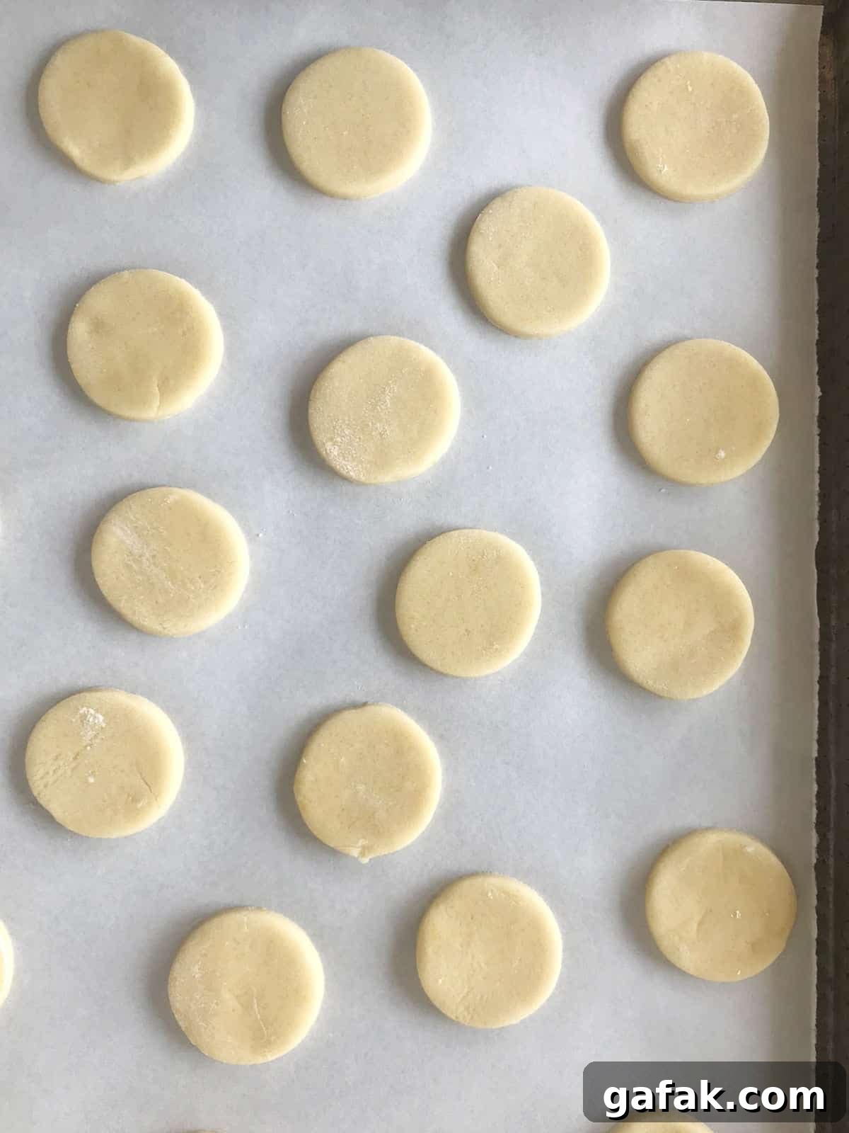Unbaked cornstarch cookie rounds on white parchment paper.