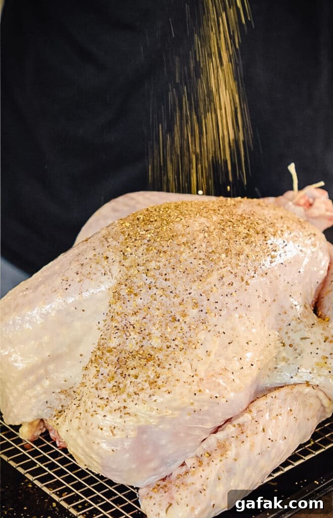 How to Smoke a Turkey: Step-by-Step Guide for Juicy Results 9 turkey seasoning blend being sprinkled over a whole uncooked turkey