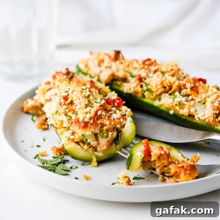 Cutting into the zucchini boats on a white plate.