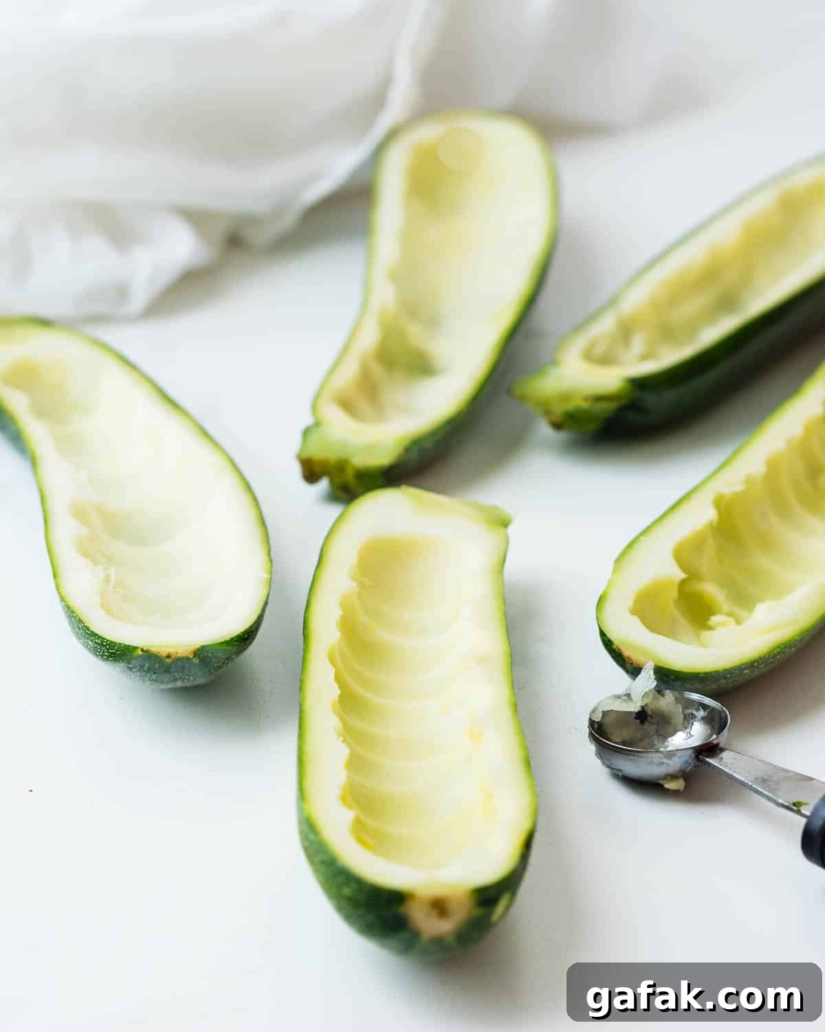 Scooping the flesh from the center of the zucchini to form a boat.