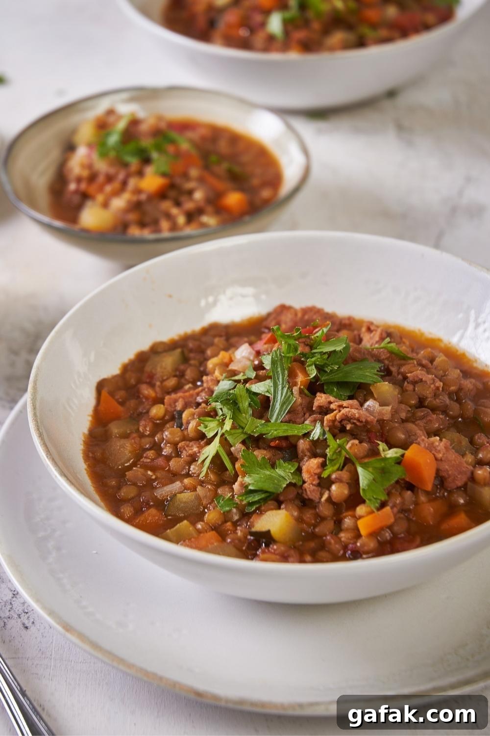 A bowl with homemade carrabba's lentil soup garnished with parsley.