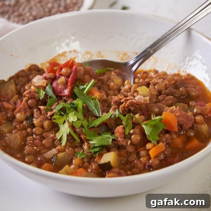 A bowl with homemade carrabba's lentil soup garnished with parsley.