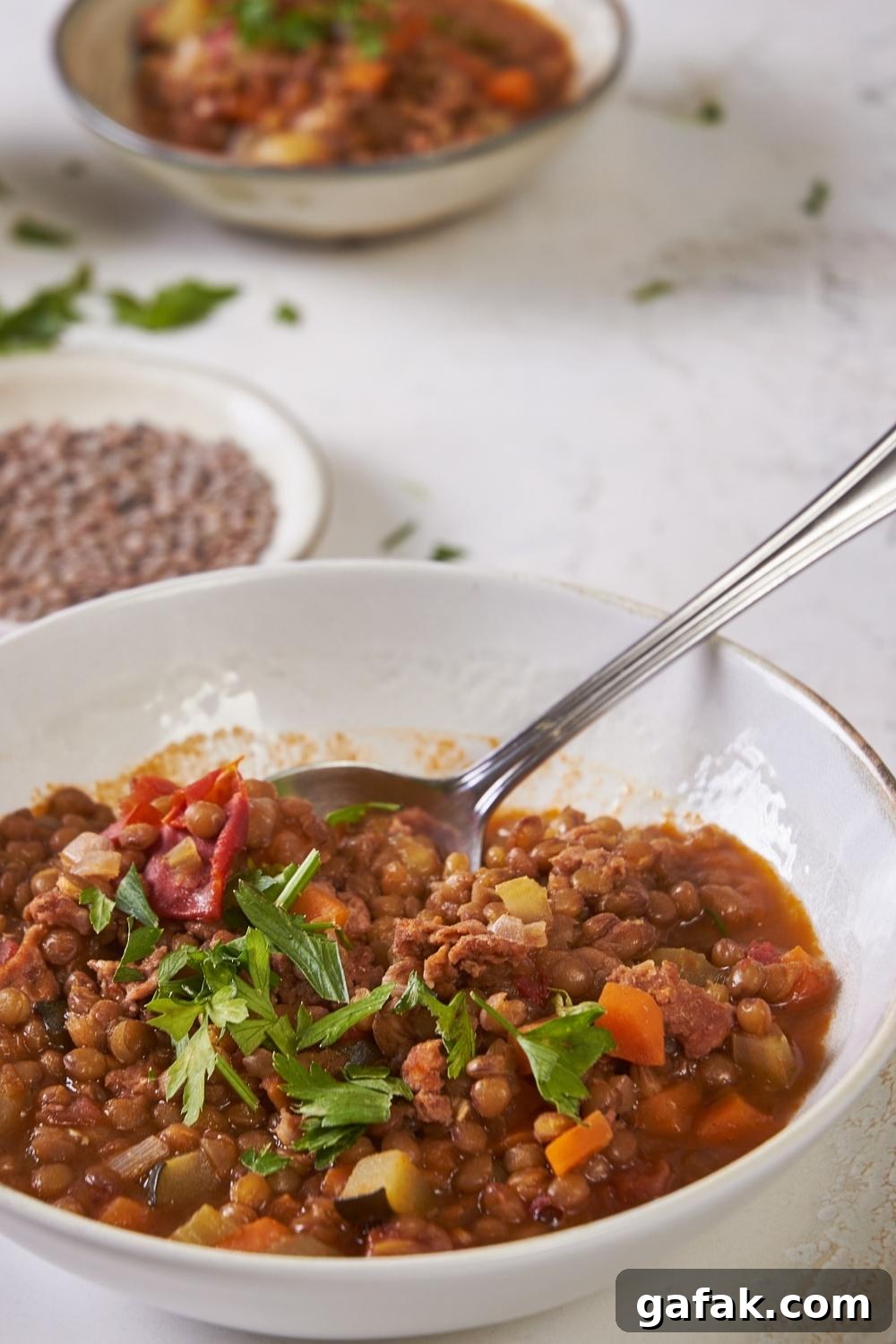 A bowl with homemade carrabba's lentil soup garnished with parsley.