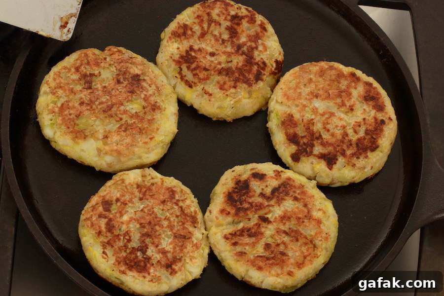Five Vegan Potato Pancakes with Leeks cooking on cast iron skillet