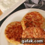 Three Vegan Potato Pancakes with Leeks plated; apple sauce and tzatziki sauce in the background and a checkered napkin to the side