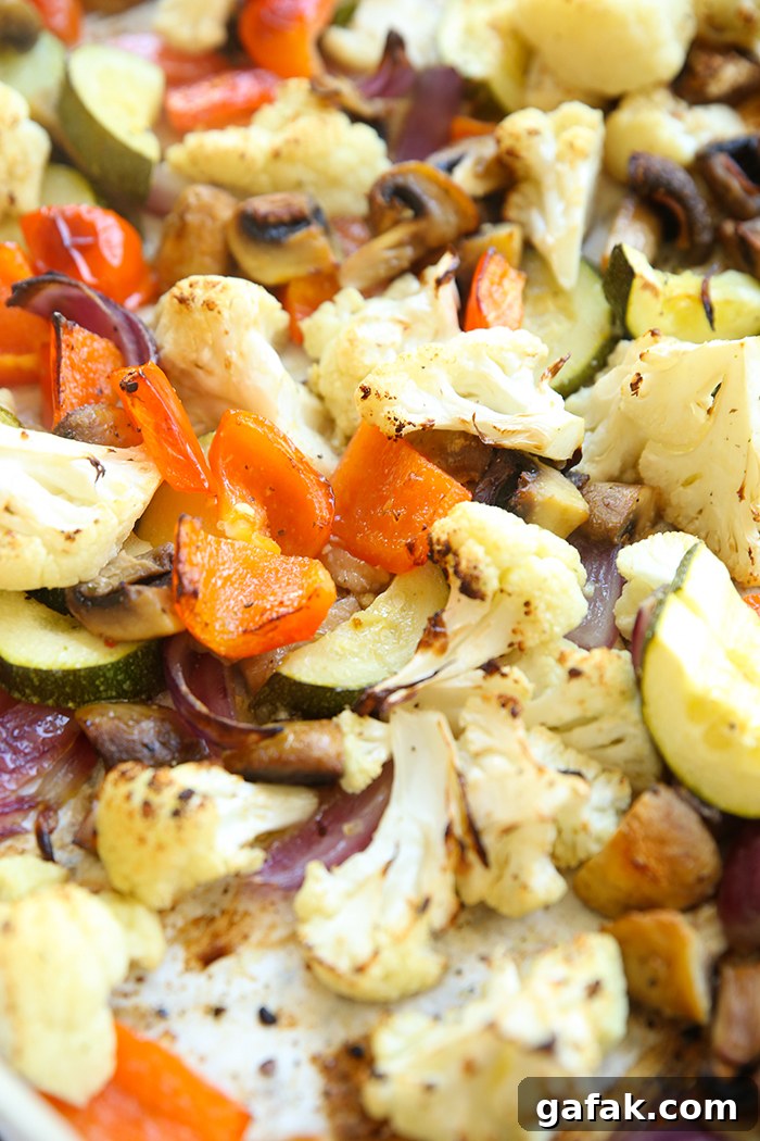 A large baking sheet lined with parchment paper filled with white balsamic roasted vegetables.